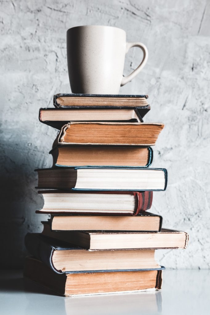 A cup of coffee on of stack of books on grey background. education, study, hobbies, read